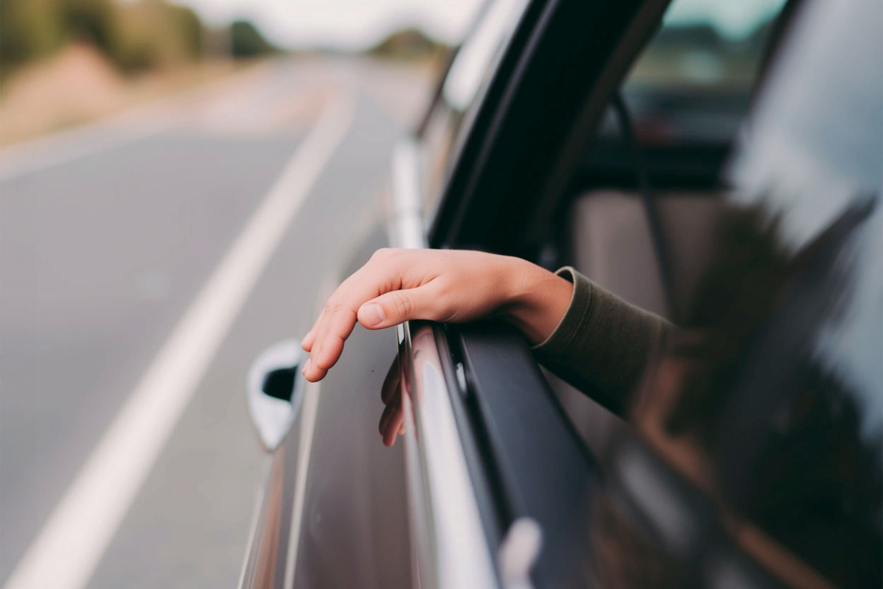 Una mano que asoma por una ventanilla de coche